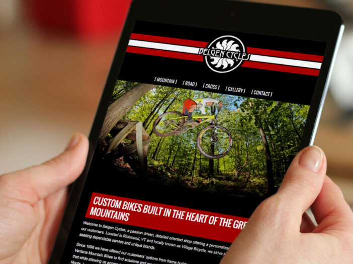 Hands holding mobile device displaying Belgen Cycles web site on