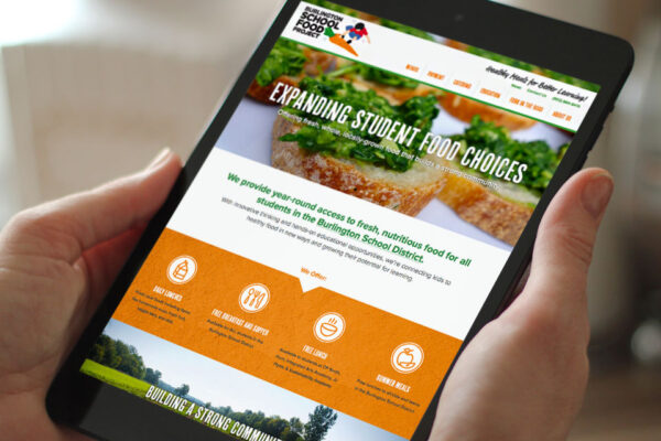 Hands holding iPad displaying Burlington School Food Project website