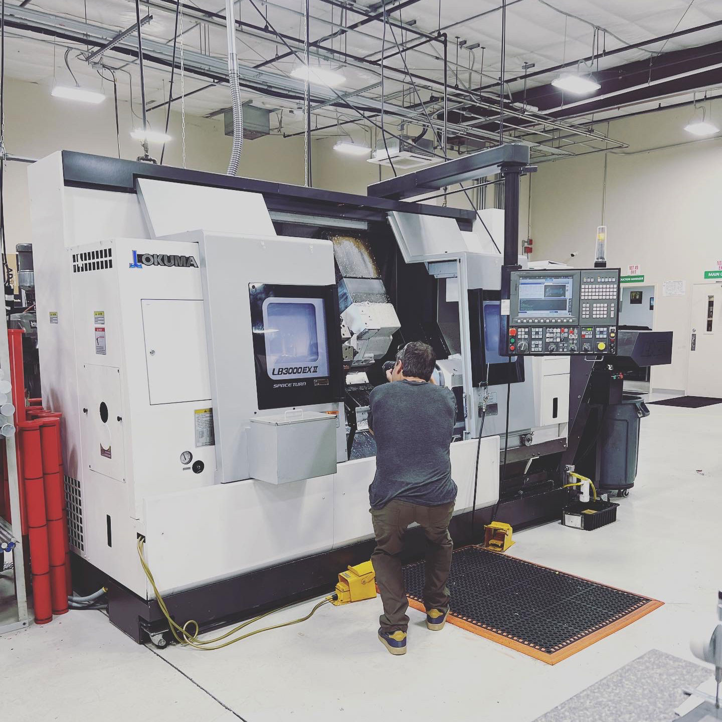 Photographer crouches to shoot machine at Pre-Tech Precision Machining