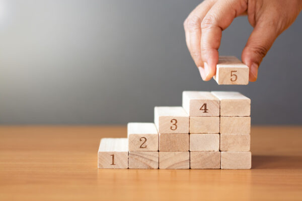 a hand building 5 steps out of blocks