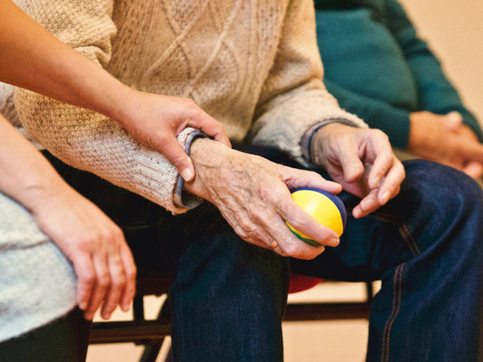 An old person holds a ball, lower body shot