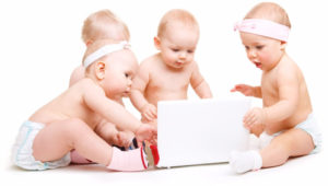 Four babies sitting around a laptop