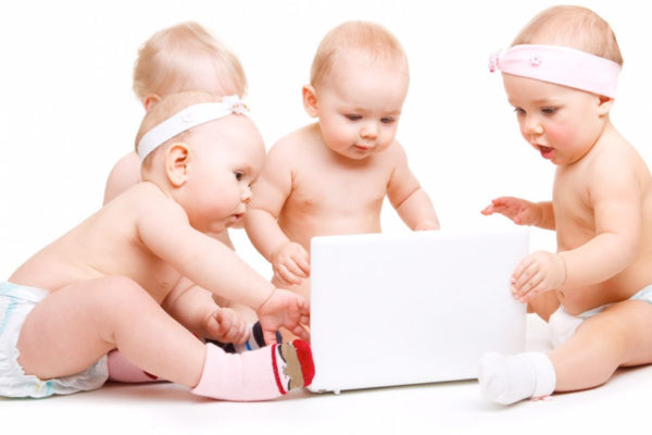 Four babies sitting around a laptop
