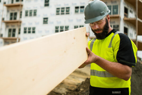 Person in hard hat holding a large piece of wood