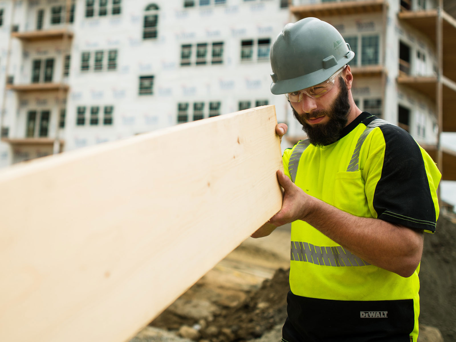Person in hard hat holding a large piece of wood