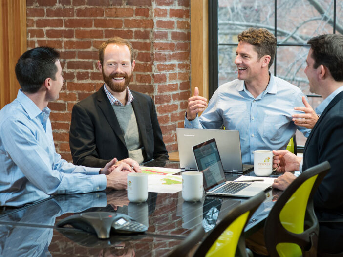 Four people at a conference table, smiling