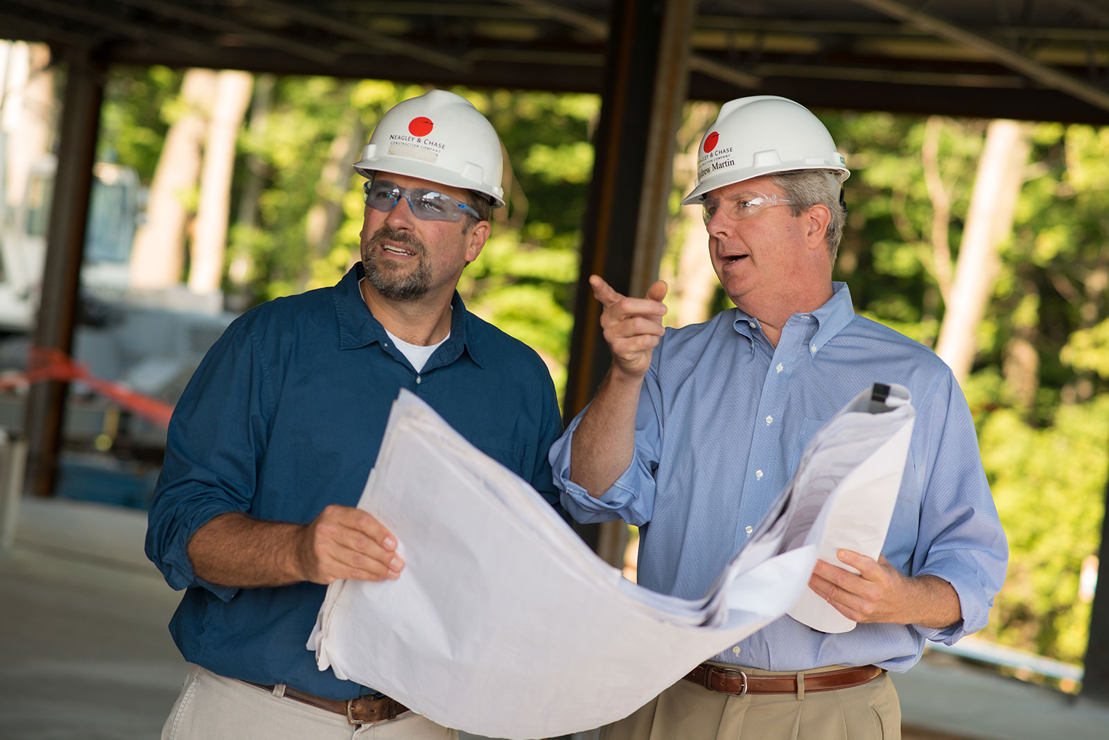 Two people in hardhats looking at blueprints