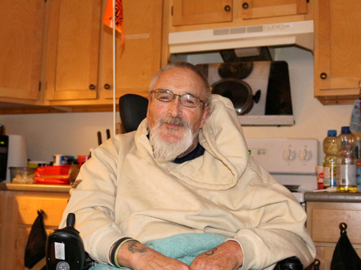 Man in a sweatshirt, sitting in a chair, facing forward