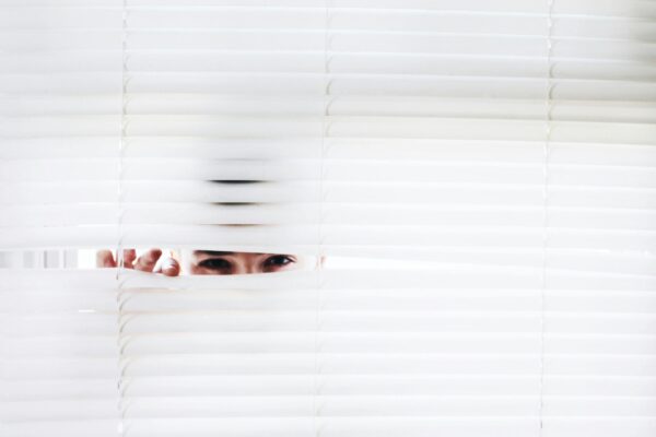 person peering through privacy blinds