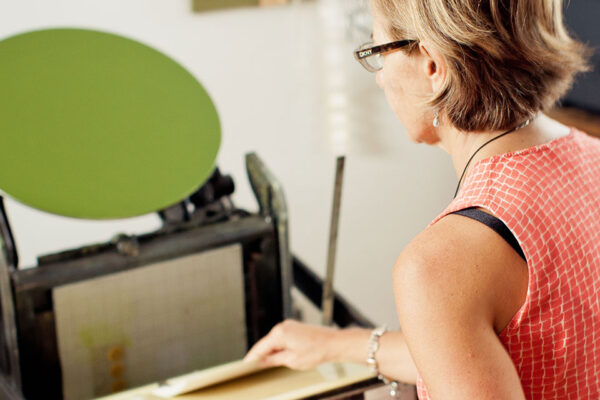 woman in glasses working at printing press